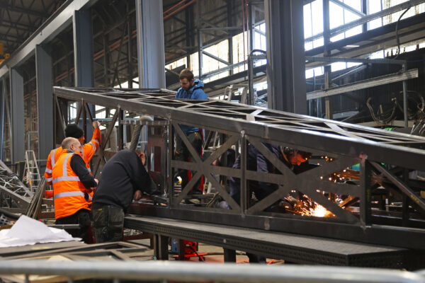 Image of Stage One team grinding a steel frame and installing bolts