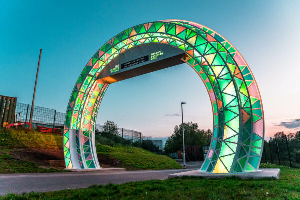 Image of large scale steel arch illuminated at dusk