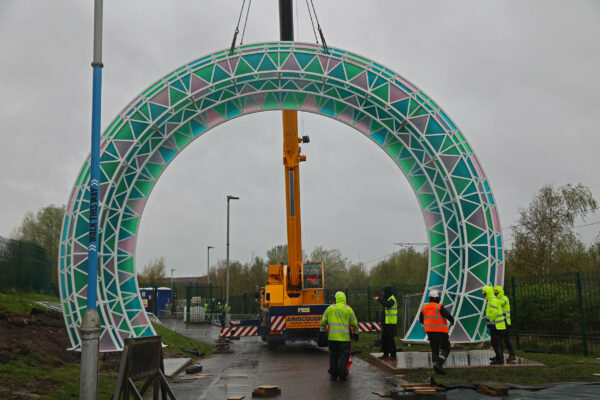 Large steel arch lifted upright by a crane